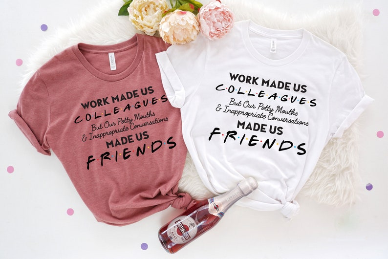 May include: Two t-shirts with the text "Work made us colleagues but our potty mouths and inappropriate conversations made us friends". The shirts are in pink and white.