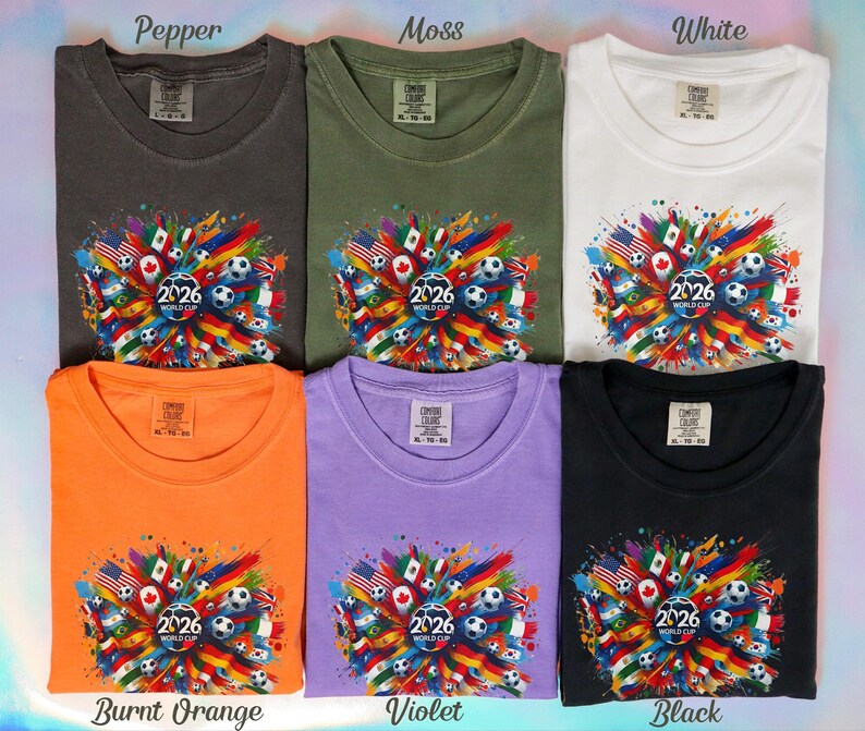 May include: Six t-shirts in various colors: pepper, moss, white, burnt orange, violet, and black. Each shirt features a colorful graphic with flags, soccer balls, and the text "2026 WORLD CUP".