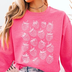 May include: A pink sweatshirt with a white outline of raspberries printed on the front.