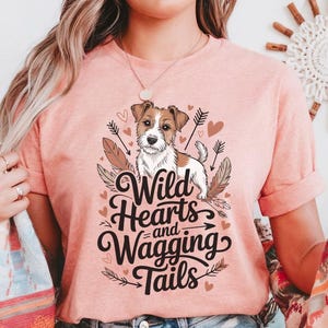 May include: A pink t-shirt with a graphic of a dog and the text "Wild Hearts and Wagging Tails".