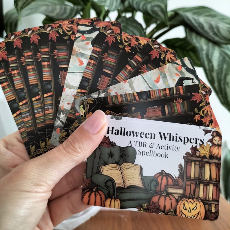 A set of small cards, each beautifully designed with Halloween-themed imagery, and titled: Halloween Whispers- A TBR and Activity Spellbook. In the colors orange, black and brown. The cards offer 27 reading prompts and 6 activities.