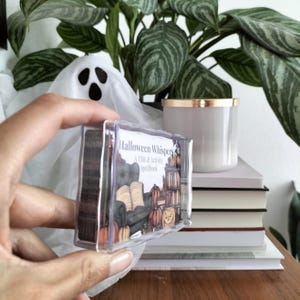 A set of small cards, each beautifully designed with Halloween-themed imagery, and titled: Halloween Whispers- A TBR and Activity Spellbook. In the colors orange, black and brown. The cards offer 27 reading prompts and 6 activities.