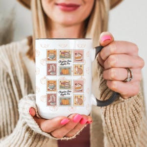 May include: White ceramic mug with a black handle and rim, featuring a repeating pattern of postage stamp-style illustrations. The stamps depict coffee cups, books, pumpkins, slices of pie, and a cat. The text "Chapter One: Apple Pie" is also visible.