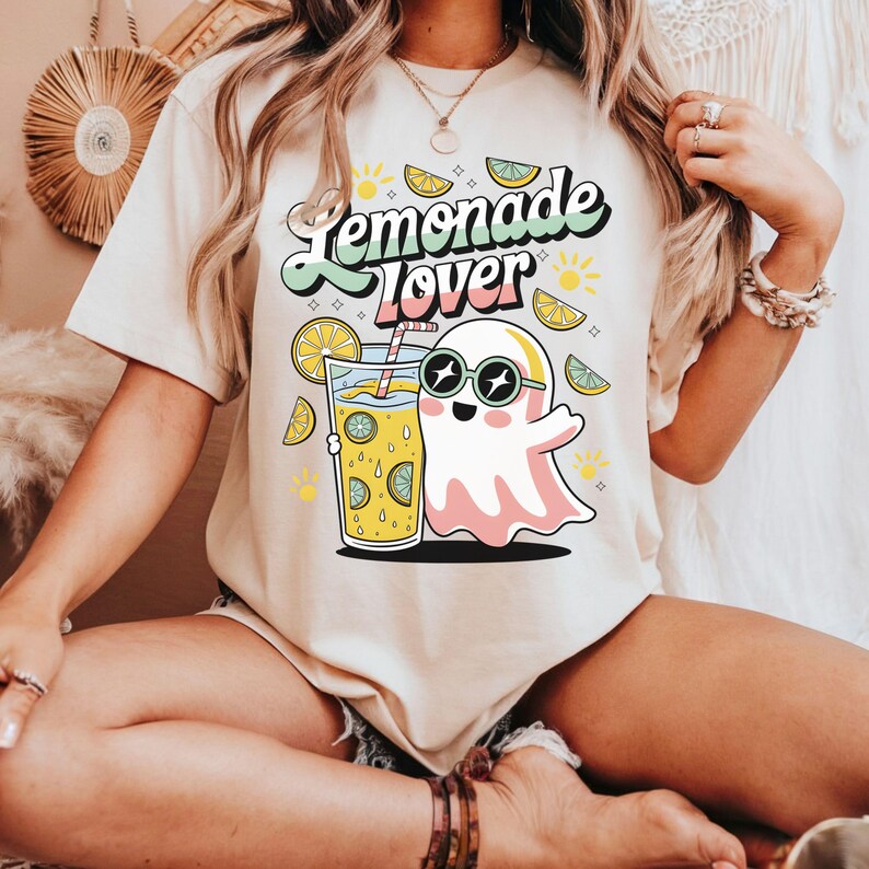 Peut inclure: T-shirt beige avec l'inscription "Lemonade Lover". Le motif pr&eacute;sente un fant&ocirc;me de dessin anim&eacute; avec des lunettes de soleil, un verre de limonade, des tranches de citron et des soleils. Design color&eacute;.