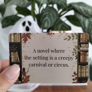 A set of small cards, each beautifully designed with Halloween-themed imagery, and titled: Halloween Whispers- A TBR and Activity Spellbook. In the colors orange, black and brown. The cards offer 27 reading prompts and 6 activities.