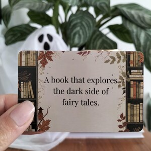 A set of small cards, each beautifully designed with Halloween-themed imagery, and titled: Halloween Whispers- A TBR and Activity Spellbook. In the colors orange, black and brown. The cards offer 27 reading prompts and 6 activities.