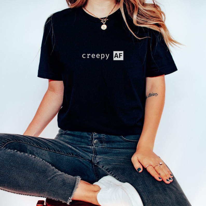 May include: A black t-shirt with the text "creepy AF" printed in white on the front.