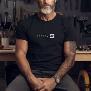 May include: A black t-shirt with the text "creepy AF" printed in white on the front.