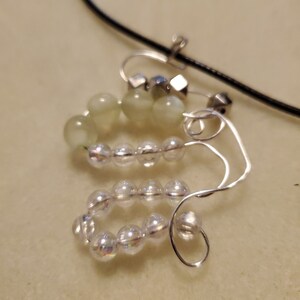 Puede incluir: Un collar de alambre plateado con cuentas de vidrio verde y transparente. El collar tiene un diseño simple y es perfecto para el uso diario.