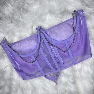 Op de afbeelding: Een lavendelkleurig doorschijnend corsettop met zilveren kettingbandjes en een veter aan de achterkant.