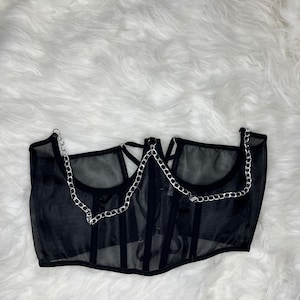 Op de afbeelding: Zwart mesh korset top met zilveren ketting details. Het korset heeft een sweetheart halslijn en een geboned bodice.