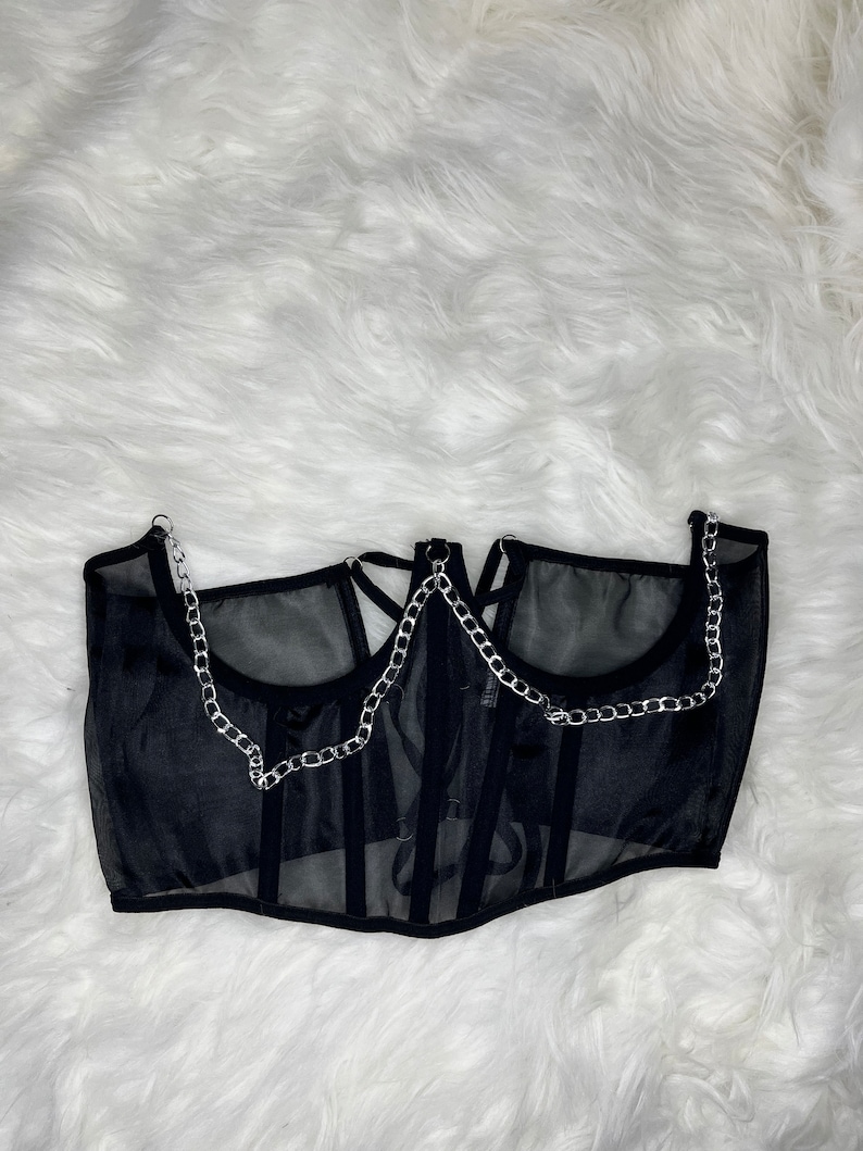Op de afbeelding: Zwart mesh korset top met zilveren ketting details. Het korset heeft een sweetheart halslijn en een geboned bodice.