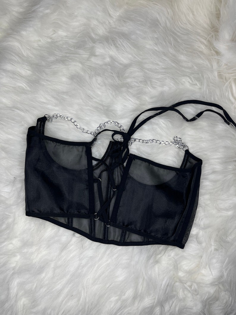 Op de afbeelding: Zwart mesh corset top met een veter aan de voorkant en een zilveren kettingdetail.