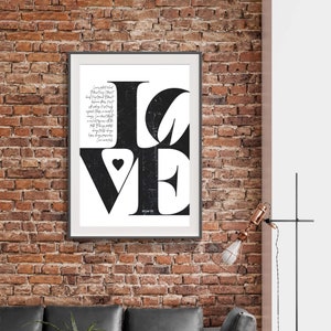Może przedstawiać: Czarno-biały druk typograficzny słowa "LOVE" z małym sercem w środku litery "V". Druk jest oprawiony w ramę i wisi na ceglanej ścianie.