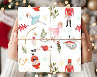 May include: A wrapped gift with a festive design featuring watercolour illustrations of ballerinas, nutcrackers, and holiday ornaments. The gift is tied with twine and set against a blurred background of Christmas lights.