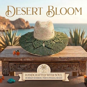 May include: A straw hat with a wide brim featuring a dark green macrame overlay in a geometric pattern. The text DESERT BLOOM is displayed above the hat, and a banner below reads HANDCRAFTED WITH SOUL BY BREEZY BOHEMIAN, PUERTO PENASCO, MEXICO.