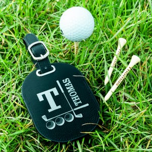 May include: Black leather luggage tag with a golf club and three golf balls, and the name "THOMAS" engraved on it.