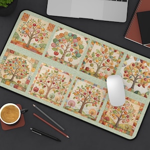 May include: A rectangular mouse pad featuring a patchwork design of apple trees in various stages of the season. The trees are filled with colorful apples and leaves, set against a light green background. A white mouse and a laptop are visible.