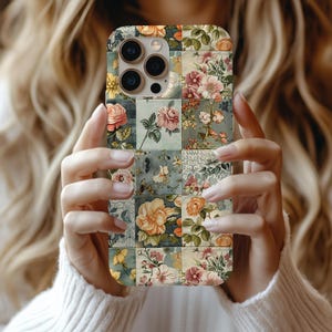 May include: A smartphone case featuring a grid-like patchwork design of various floral patterns in shades of muted pink, orange, yellow, and sage green. The case has a cutout for a triple-lens camera system and a flash on the upper left corner.