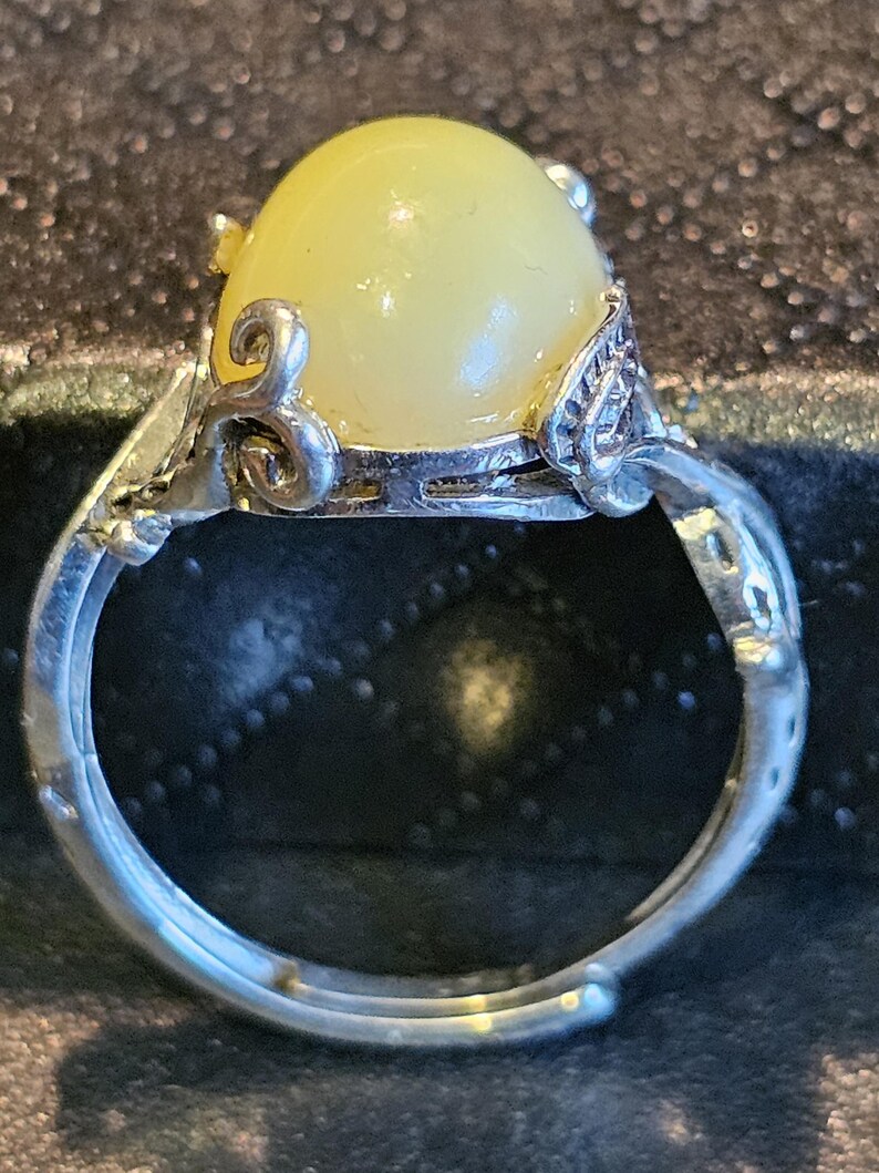 May include: A silver ring with a yellow oval-shaped gemstone set in a decorative silver setting.