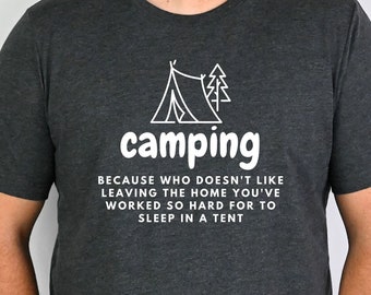 May include: A dark grey t-shirt with a white graphic of a tent and a tree. The text "camping" is written in white below the graphic. The text "Because who doesn't like leaving the home you've worked so hard for to sleep in a tent" is written in white below the graphic.