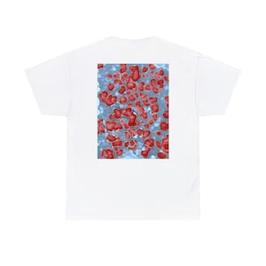 May include: A white t-shirt featuring a rectangular graphic print on the back. The print displays a microscopic view of red, irregular, cell-like clusters set against a pale blue, textured background, creating a scientific and biological visual pattern.