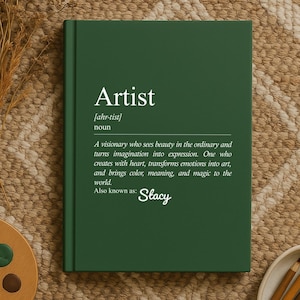 May include: A dark green book with the word "Artist" in white, along with a definition. A wooden palette with paint and a brush, dried flowers, and pencils in a small bowl are also visible.