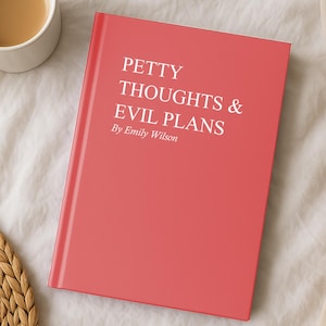 May include: A red book titled "Petty Thoughts & Evil Plans" by Emily Wilson. A white mug of coffee sits to the left of the book. The book and mug are on a white surface.
