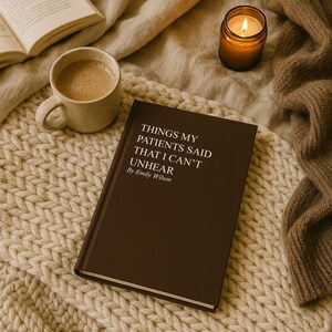 May include: A brown book titled "THINGS MY PATIENTS SAID THAT I CAN'T UNHEAR" by Emily Wilson, rests on a cream-colored knitted blanket. A cup of coffee and a lit candle in a glass jar are also present.