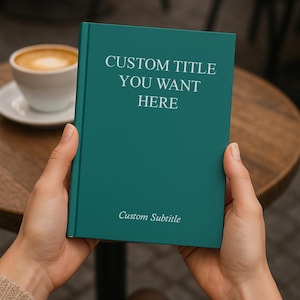 May include: A teal book with the text "CUSTOM TITLE YOU WANT HERE" and "Custom Subtitle" in white. The book is held by hands, with a blurred background of a table and a cup of coffee.