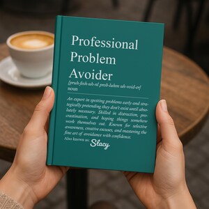 May include: A teal book titled "Professional Problem Avoider" is held by hands. The book's definition is printed in white, with the name "Stacy" at the bottom. A cup of coffee sits on a wooden table in the background.