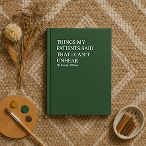 May include: A hardcover book with a dark green cover, titled "THINGS MY PATIENTS SAID THAT I CAN'T UNHEAR By Emily Wilson." The book is on a textured, neutral-toned surface, with a palette, paint brush, and pencils.
