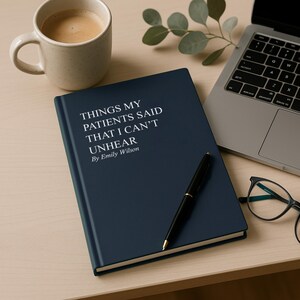 May include: A navy blue hardcover journal with the text "THINGS MY PATIENTS SAID THAT I CAN'T UNHEAR By Emily Wilson" in white. A black pen rests on the journal, next to a laptop, a cup of coffee, and eyeglasses.