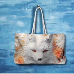 Può includere: Borsa tote bianca con una volpe bianca con occhi rossi e fiori arancioni sul davanti.