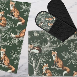 May include: A set of three kitchen accessories featuring a green and white fox pattern. The set includes a potholder, a hot pad, and a tea towel.