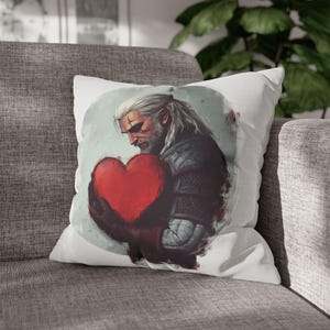 May include: White cushion with a colourful illustration of a man holding a red heart. The man has dark hair and a beard and is wearing a dark jacket. The background is a light grey watercolour wash.