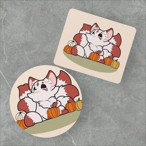 May include: A white and red fox with a fluffy tail sits surrounded by orange pumpkins. The fox has a white face with black eyes and a pink nose. The background is a light brown.