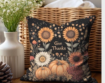 May include: A black throw pillow with a floral design featuring sunflowers, pumpkins, and other fall foliage. The pillow has the text "Give Thanks" in the center.