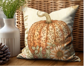 May include: A decorative throw pillow featuring a watercolor-style pumpkin design. The pumpkin is orange with brown spots and a curved stem. The pillow also includes floral and leaf accents in shades of brown, green, and cream, perfect for fall decor.