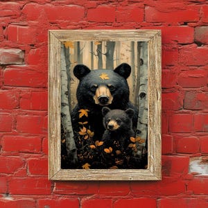May include: A framed art print featuring a black bear and a cub in a forest setting. The bears are surrounded by birch trees and autumn leaves. The artwork is displayed against a red brick wall.