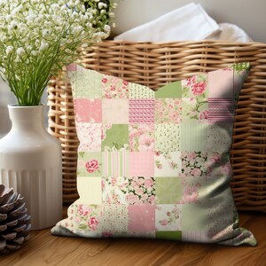 May include: Square patchwork pillow with a floral pattern in shades of pink, green, and white. The pillow is made up of various fabric squares with different floral and striped designs. The pillow is resting on a wooden surface.
