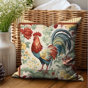 May include: A decorative throw pillow with a colorful rooster design. The rooster is red, yellow, blue, and green, and is surrounded by floral patterns. The pillow is white with a red, yellow, and brown border.