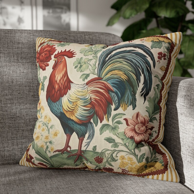 May include: A decorative throw pillow with a colorful rooster design. The rooster is surrounded by floral patterns in shades of red, yellow, blue, and green. The pillow has a cream-colored background and a brown and yellow striped border.