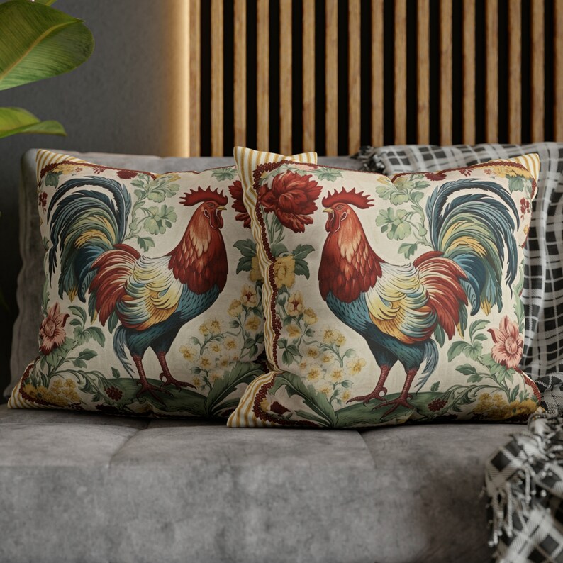 May include: Two decorative throw pillows with a cream background and a colorful rooster design. The roosters are depicted in a vintage style with red, blue, and yellow feathers. The pillows feature a floral pattern with yellow, white, and green accents.