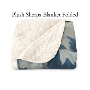 May include: A folded plush sherpa blanket with a white sherpa side and a blue and white floral print side.