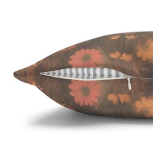 May include: A decorative pillow with a floral pattern featuring red flowers on a brown background. The pillow has a zipper closure with a striped interior. The overall design has a vintage or rustic aesthetic.
