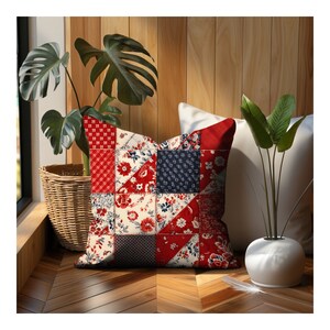 May include: Red, white, and blue patchwork pillow with a floral pattern. The pillow is sitting on a wooden floor with a plant in a wicker basket and a white vase in the background.