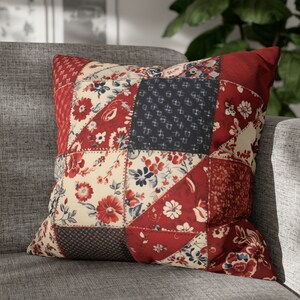May include: A red, white, and blue patchwork pillow with a floral pattern. The pillow is made of different fabrics and has a quilted design.