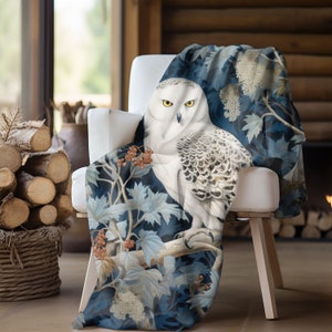 May include: A white snowy owl with yellow eyes perched on a branch with blue and white leaves. The owl is surrounded by a dark blue background with white flowers.