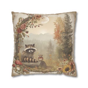 May include: A decorative throw pillow with a whimsical illustration of a raccoon, an owl, and a mushroom in a forest setting. The background features a misty forest with a full moon and a floral border.